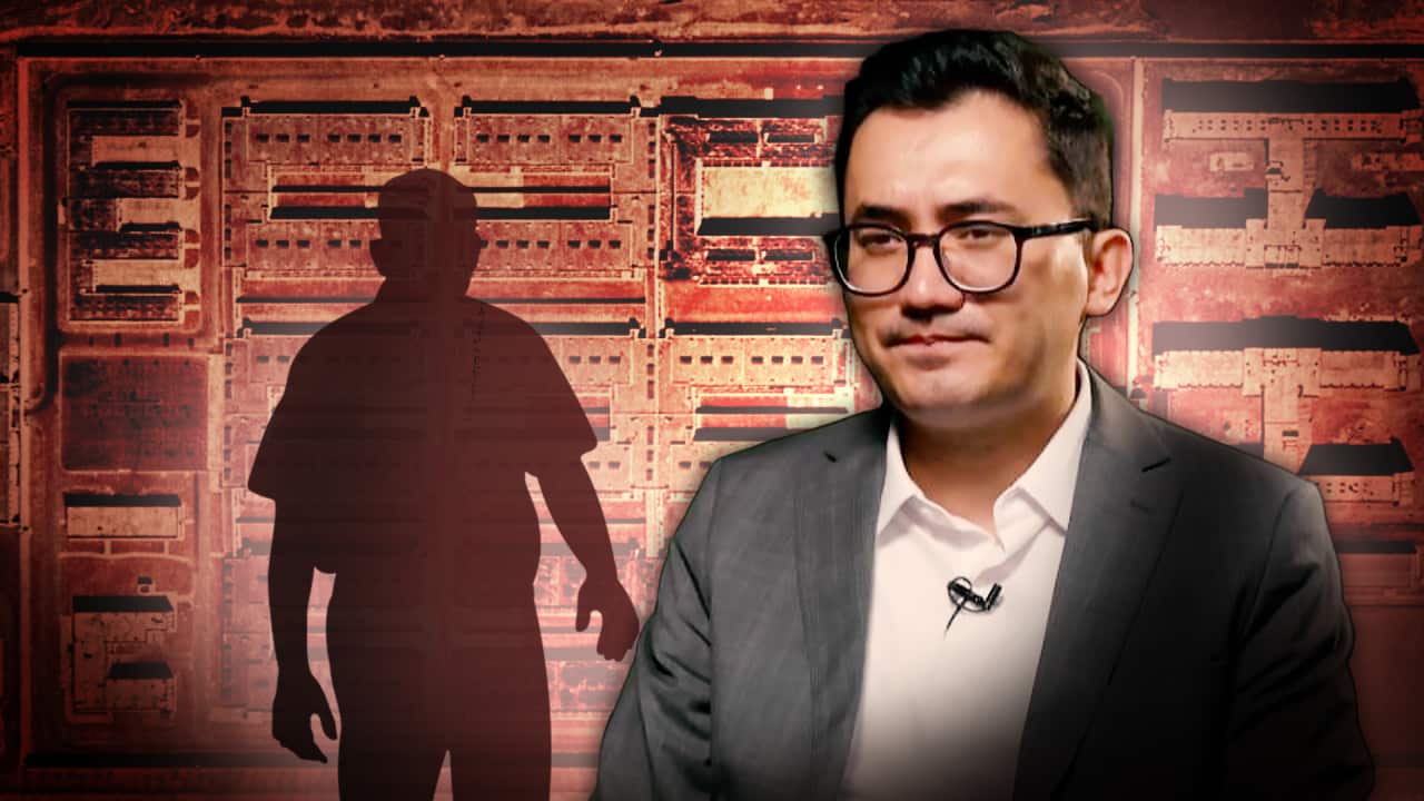 A man with glasses. A digitally altered background shows a prison-like facility and the shadow of a man.