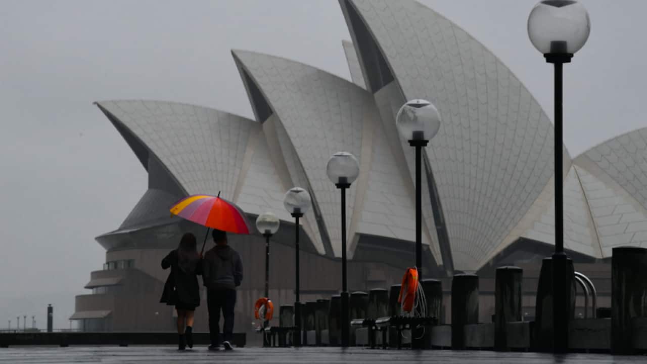Pedestrians walk past the Sydney Opera House during wet weather in Sydney, Wednesday, November 10, 2021