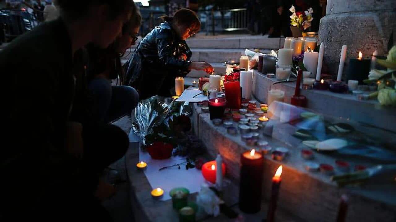 A woman lits a candle near flowers and messages displayed in front of the city hall of the Normandy city of Saint-Etienne du Rouvray on July 26, 2016. (Getty Images)