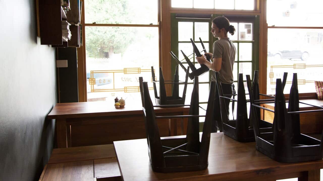 Waiter packing up cafe or restaurant chairs