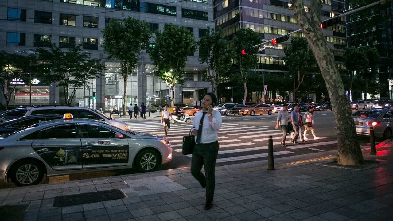 An office worker leaves for the day at 8 p.m. with many buildings still lit up in Seoul, South Korea.