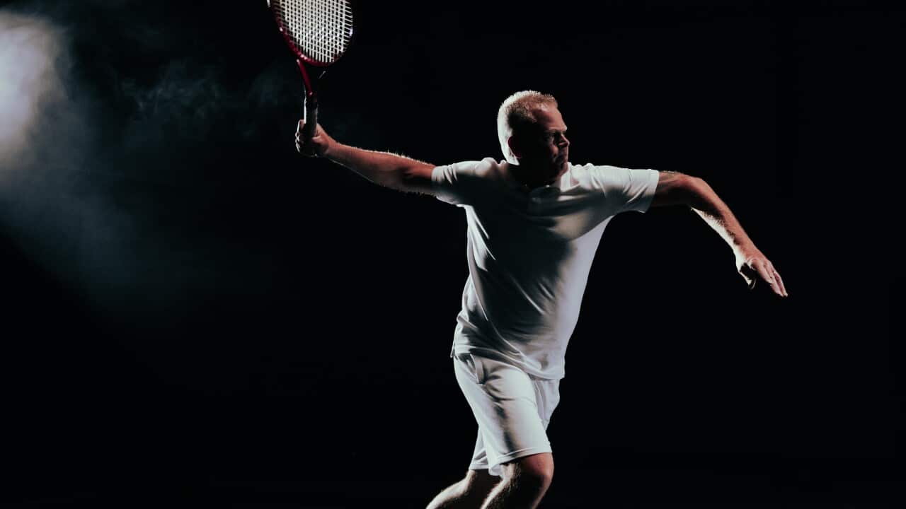 A man in tennis clothes swings a tennis racquet.