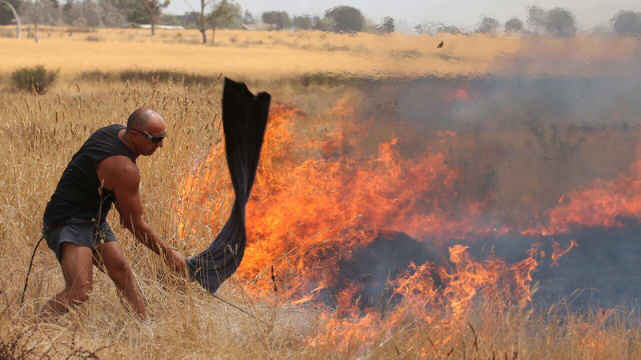 Residents with buckets battle a fast moving grass fire