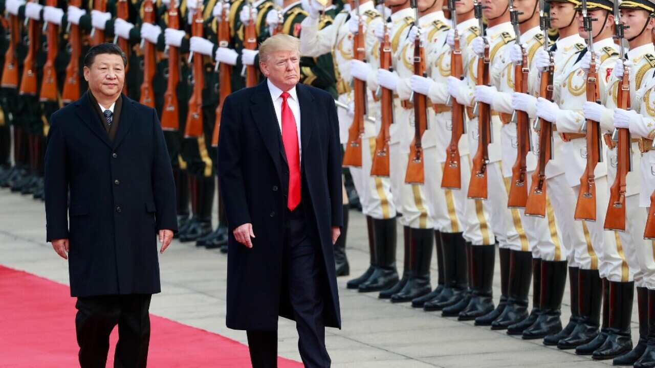 File: US President Donald J. Trump (C) and his Chinese counterpart Xi Jinping (L) review honour guards in November 2017