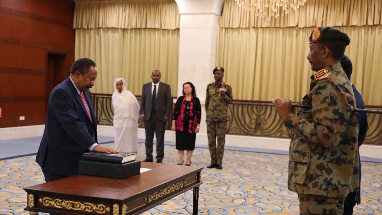 Sudan's new Prime Minister Abdalla Hamdok (L) swears in as General Abdel Fattah Abdelrahman Burhan (R) during a ceremony at the presidential palace in Sudan
