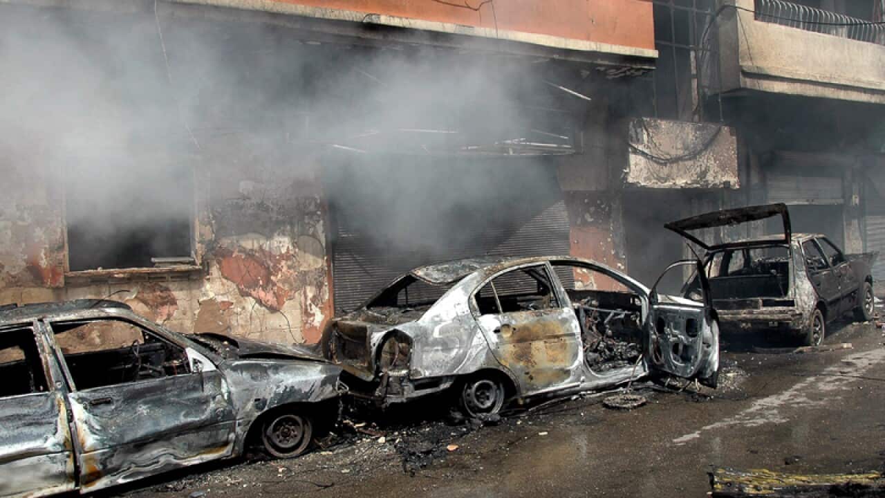 Smoke rises from burnt-out cars at the site of a car bomb explosion