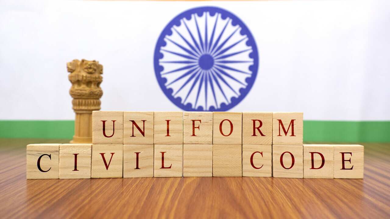 Concept of One law for all called Uniform Civil code or UCC in Indian constitution in wooden block letters and Indian flag as a background