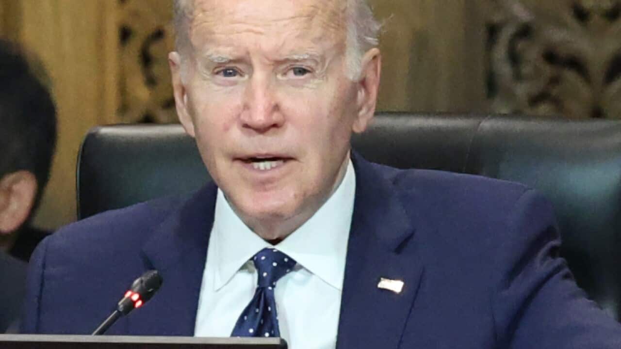 Joe Biden sitting at a table in front of a microphone.