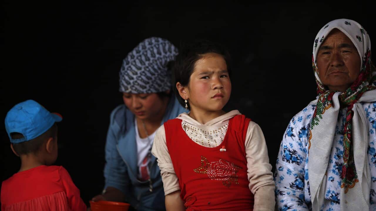 A girl and women of the Uighur ethnic group look on in Yopurga village of Kashgar, Xinjiang Uighur Autonomous Region, China