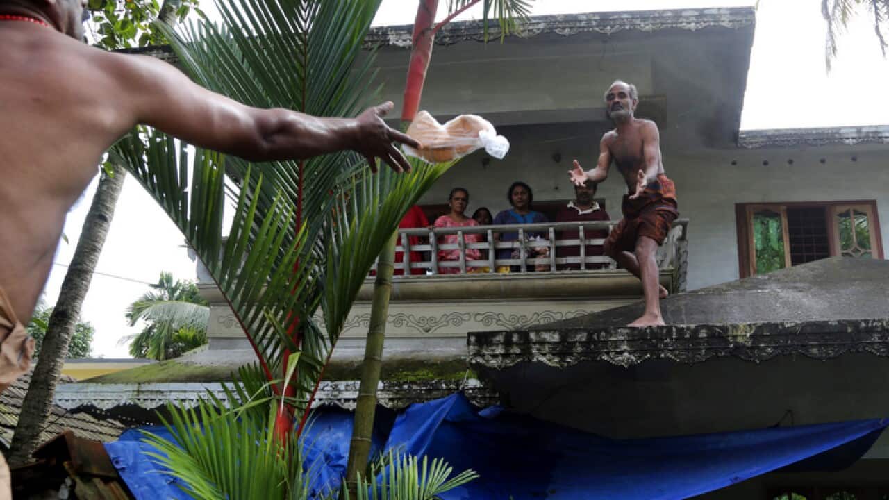 A volunteer throws a pack of bread towards a family stranded in a flooded area in Chengannur in the southern state of Kerala, India.