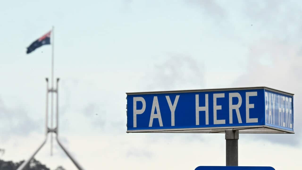 A pay here sign board with the Australian flag in the background.