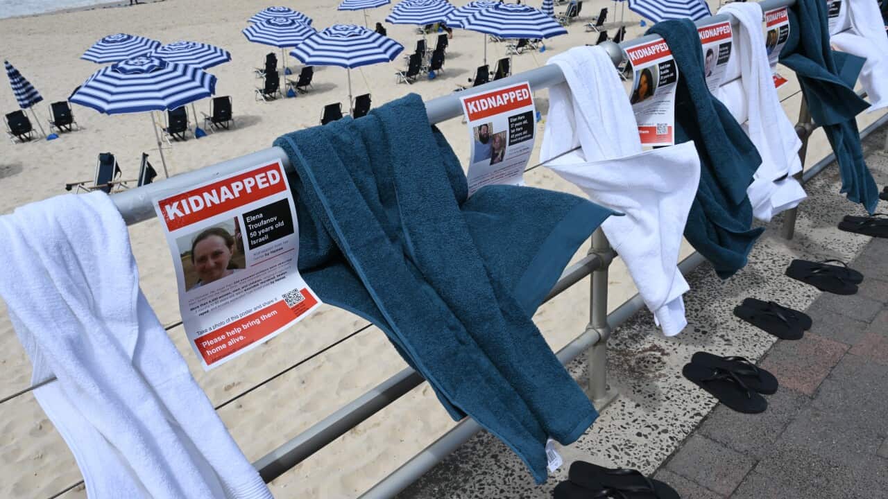 Towels and posters that have "Kidnapped" written on them hung along a fence at a beach.