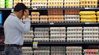 A man in front of the eggs section at a supermarket