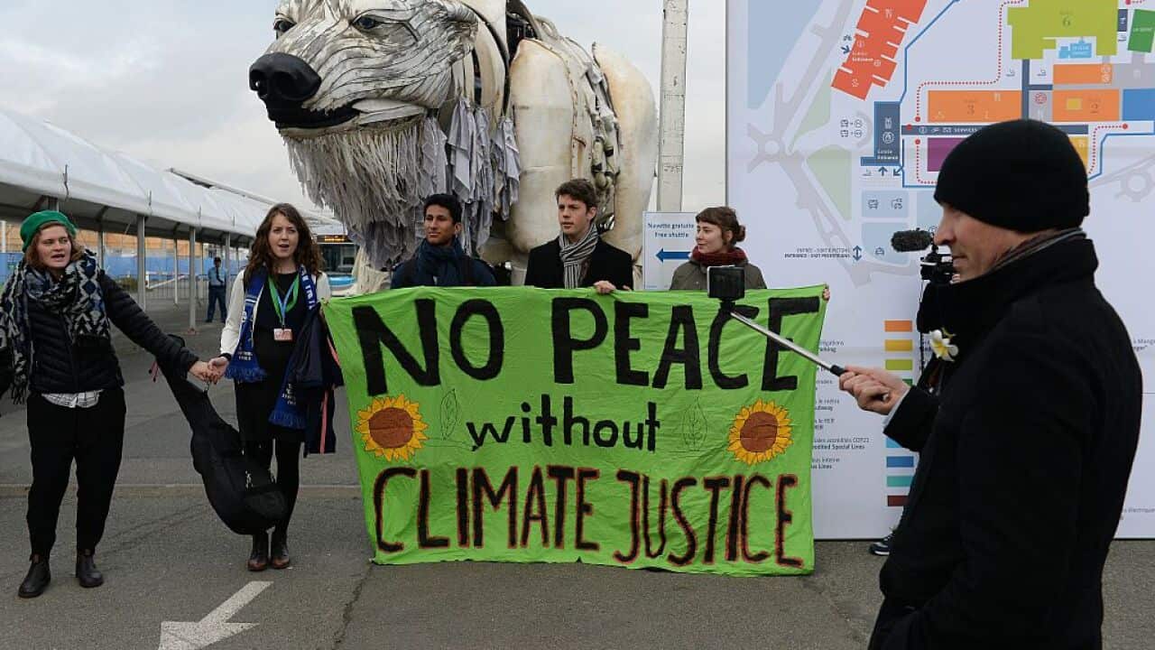 Activists hold a banner reading 'No peace without climate justice' in front of a giant polar beer puppet called Aurora by environmental organization Greenpeace during a demonstration at the venue of the COP21 United Nations climate change conference
