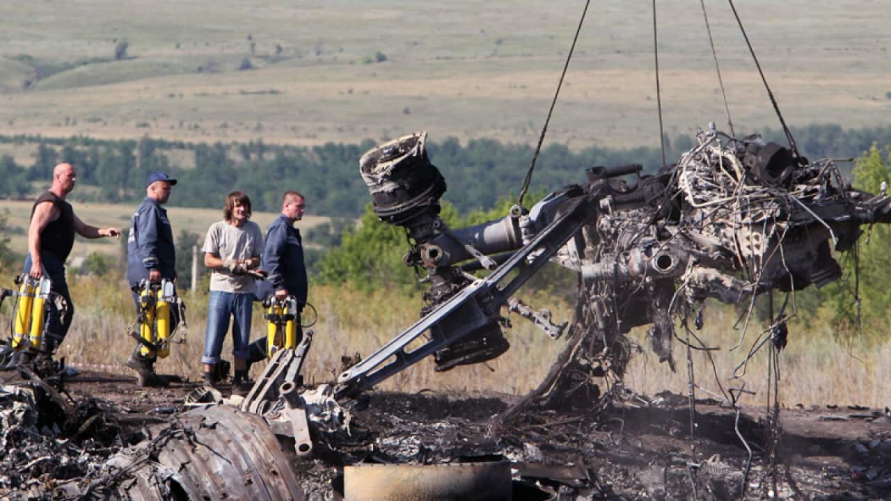 Ukrainian workers handle debris at the main crash site flight MH17