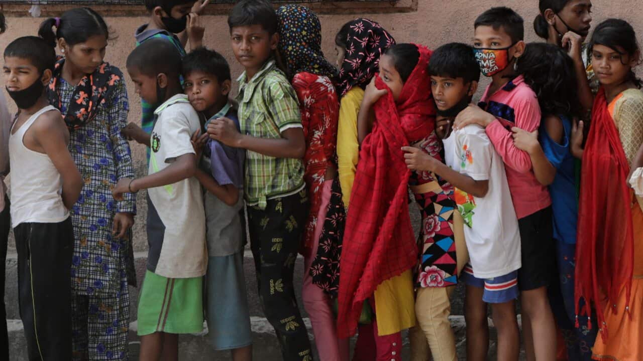 Children wait in a queue to receive food distributed in a slum during India's coronavirus lockdown.