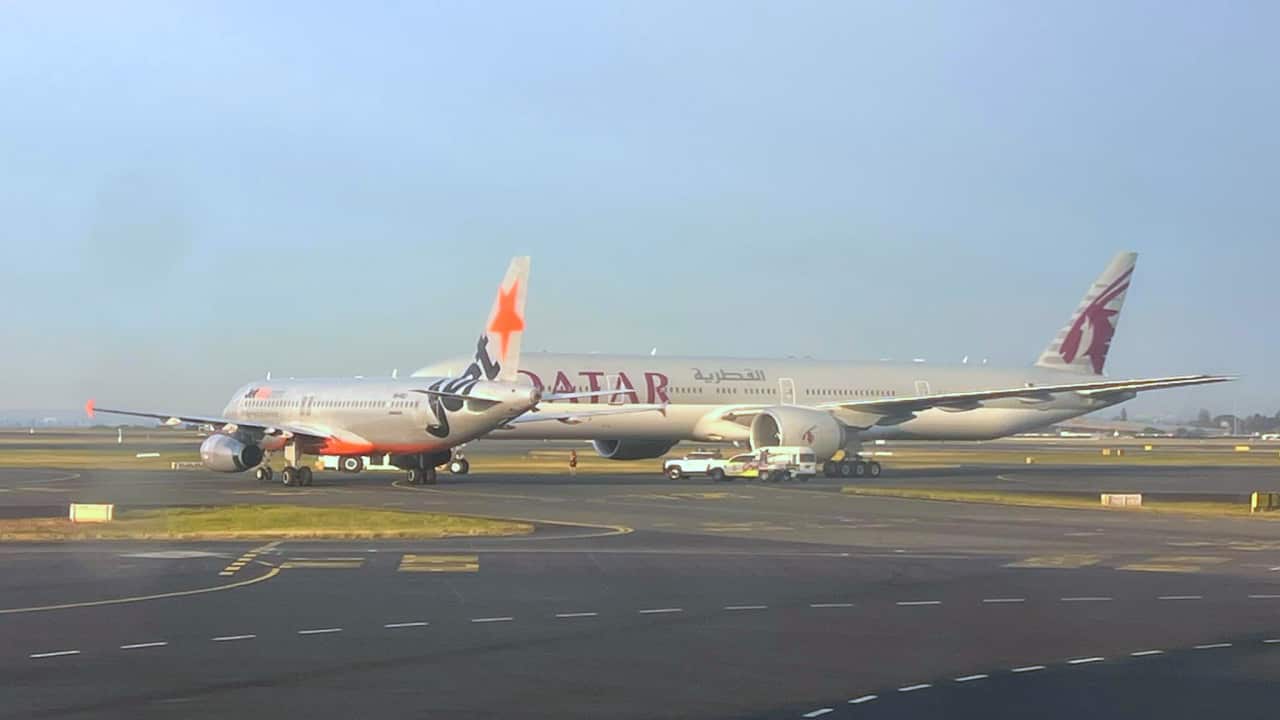 Two planes sit very close together on an airport runway.