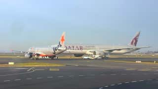 Two planes sit very close together on an airport runway.