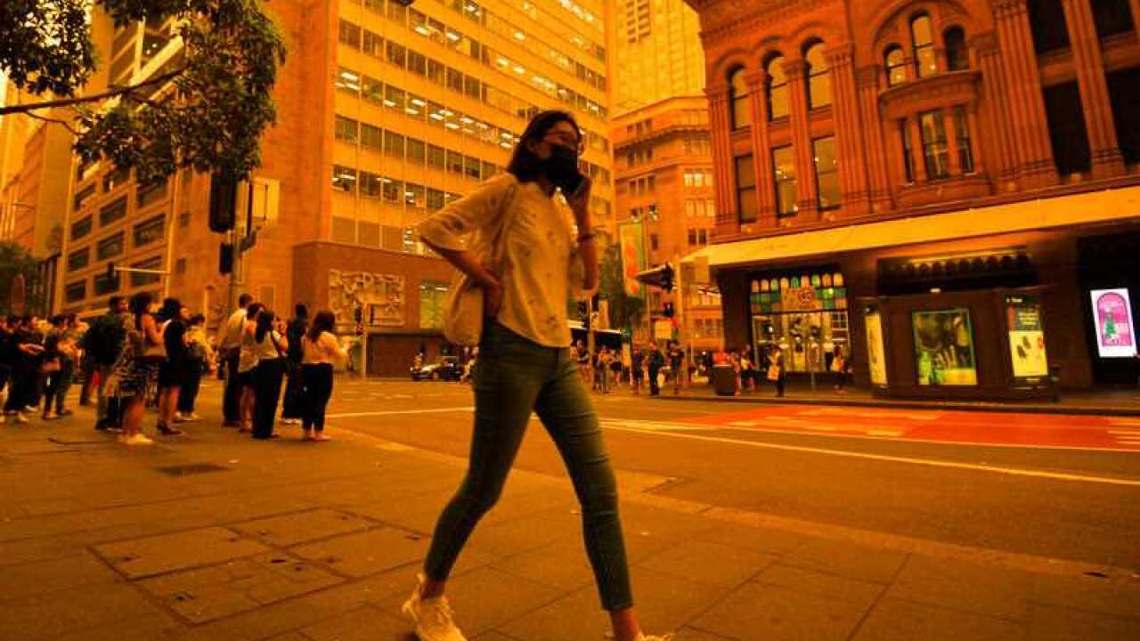 A woman wearing a mask is seen in the Sydney CBD as smoke haze blankets Sydney, 6 December 2019