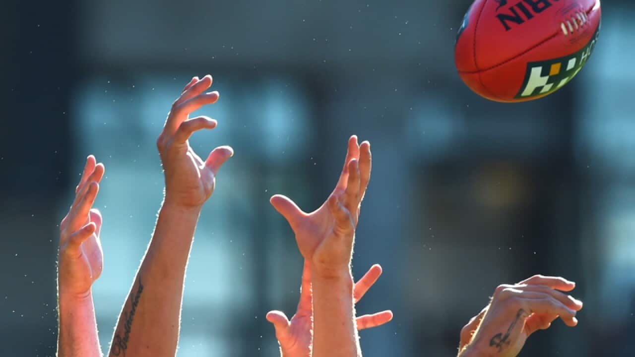 An assortment of hands reach for a Shrrin AFL football
