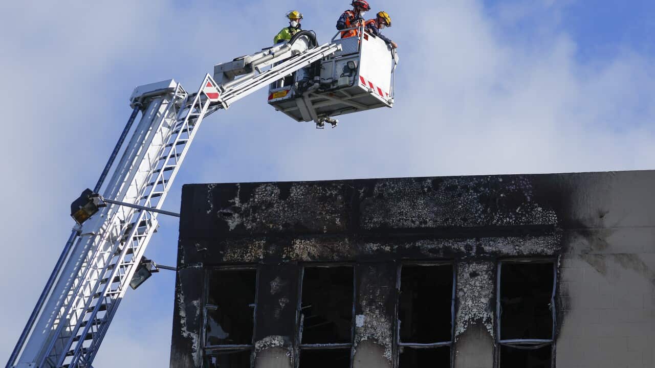 Firemen on a crane inspecting top floor of hostel