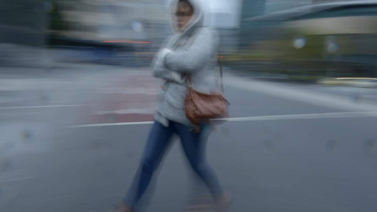 A woman rugs up as she walks through the city in Melbourne