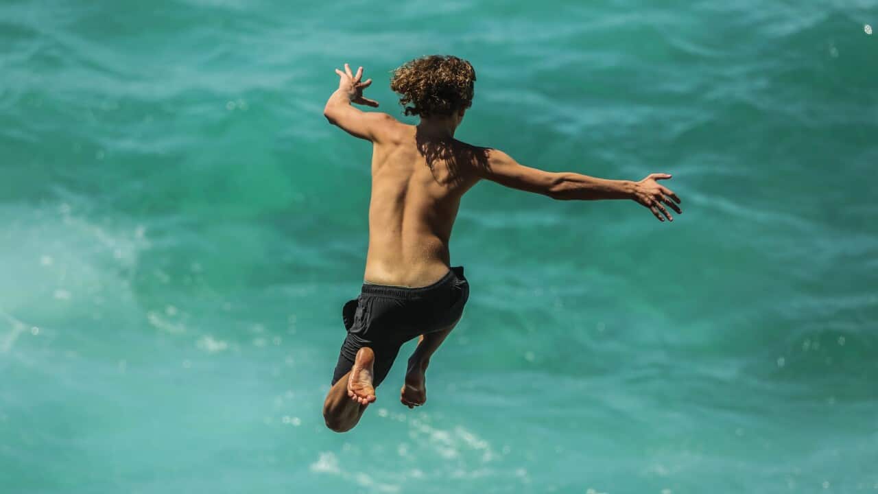 Beachgoers are seen jumping off rocks on Bronte Beach in Sydney.