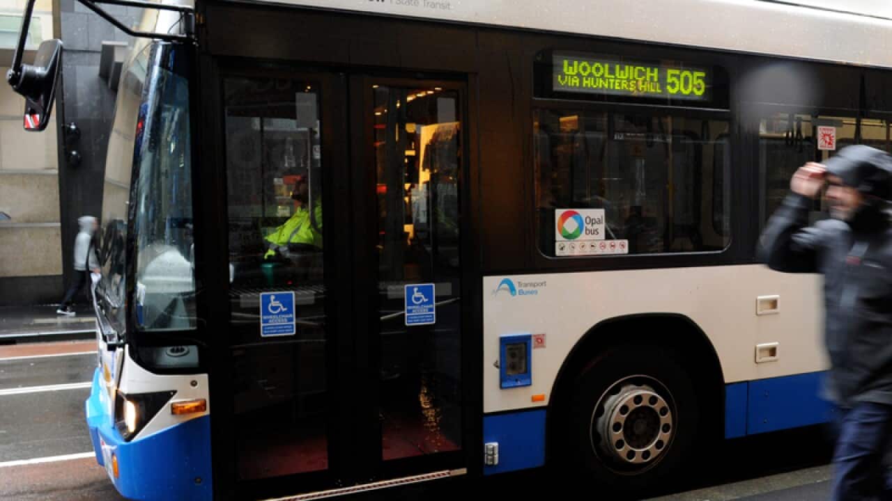 Pedestrians pass a bus on George Street