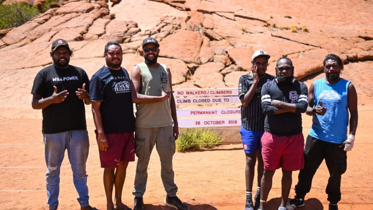 Members of the Mala Band pose for photographs near the newly installed sign indicating the permanent closure of the climb at Uluru.