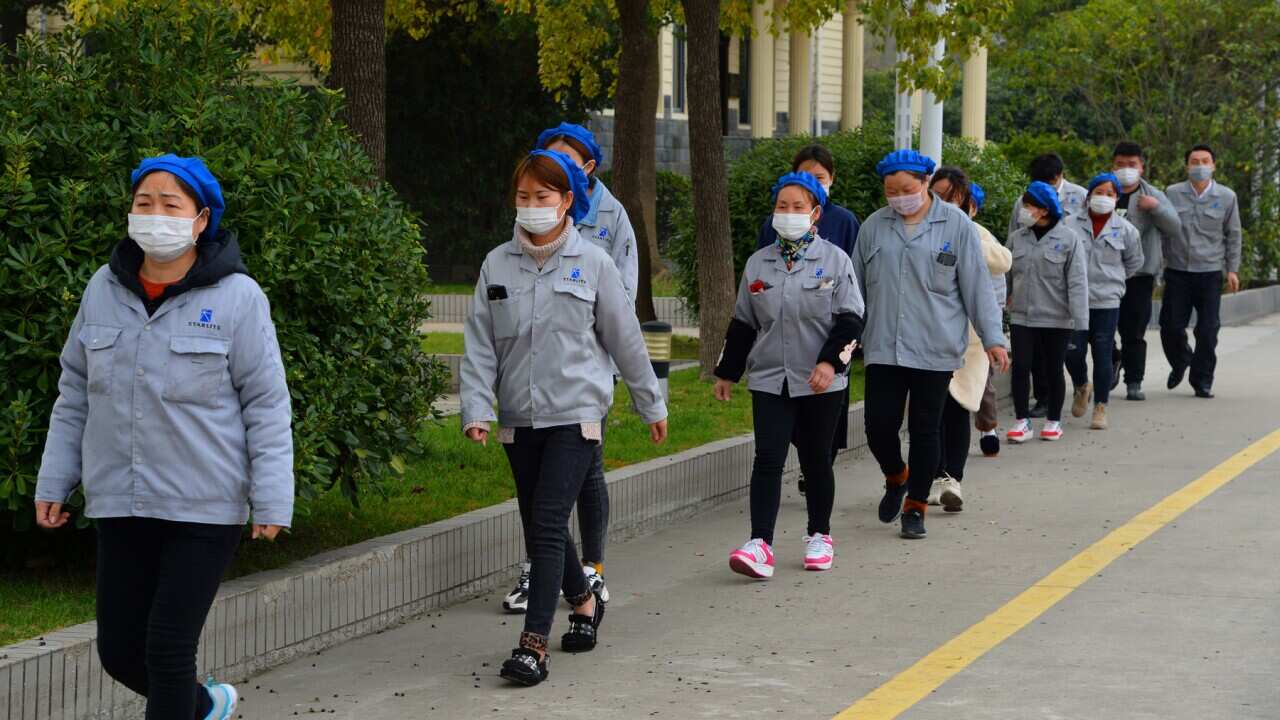 Masked female Chinese workers walk alone and separately for prevention of the novel coronavirus and pneumonia in Taicang City, east China