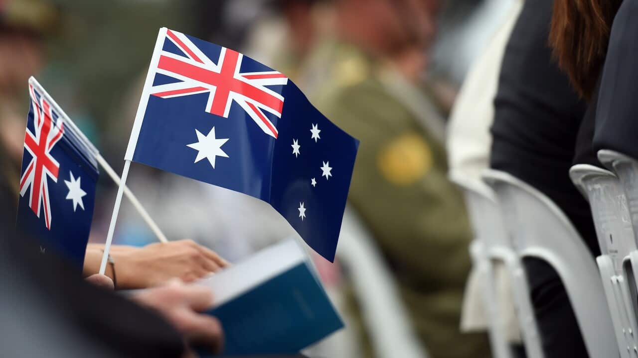 Memmbers of the public hold flags at an Australia Day Citizenship Ceremony and Flag Raising event in Canberra.