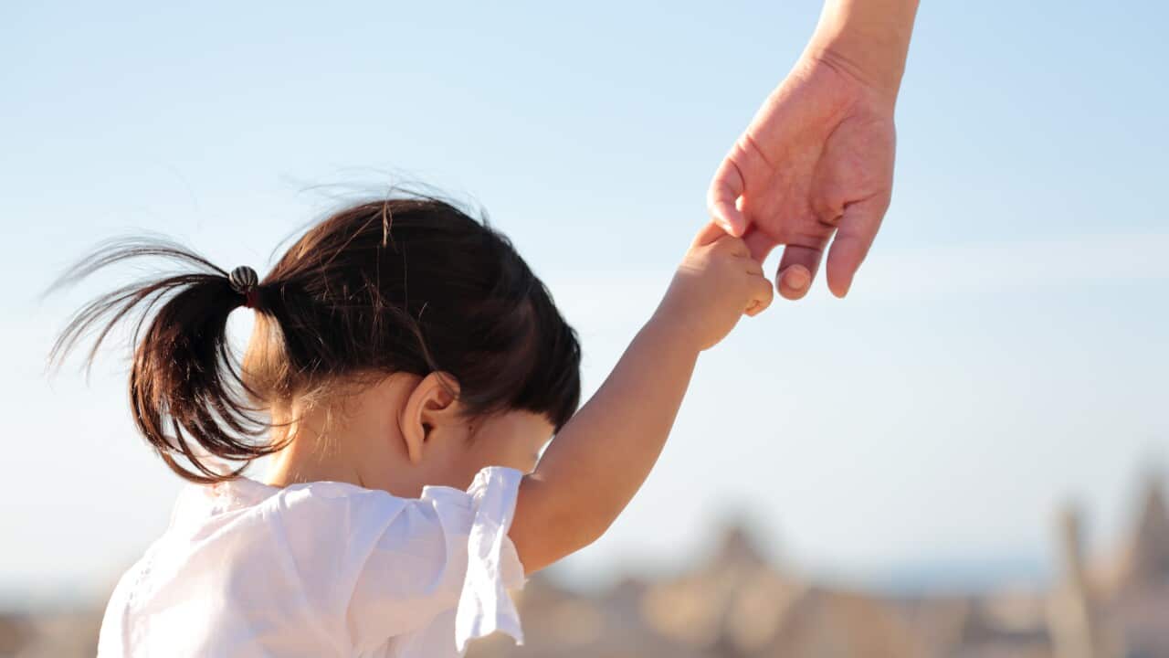 Father and daughter walking hand in hand on beach