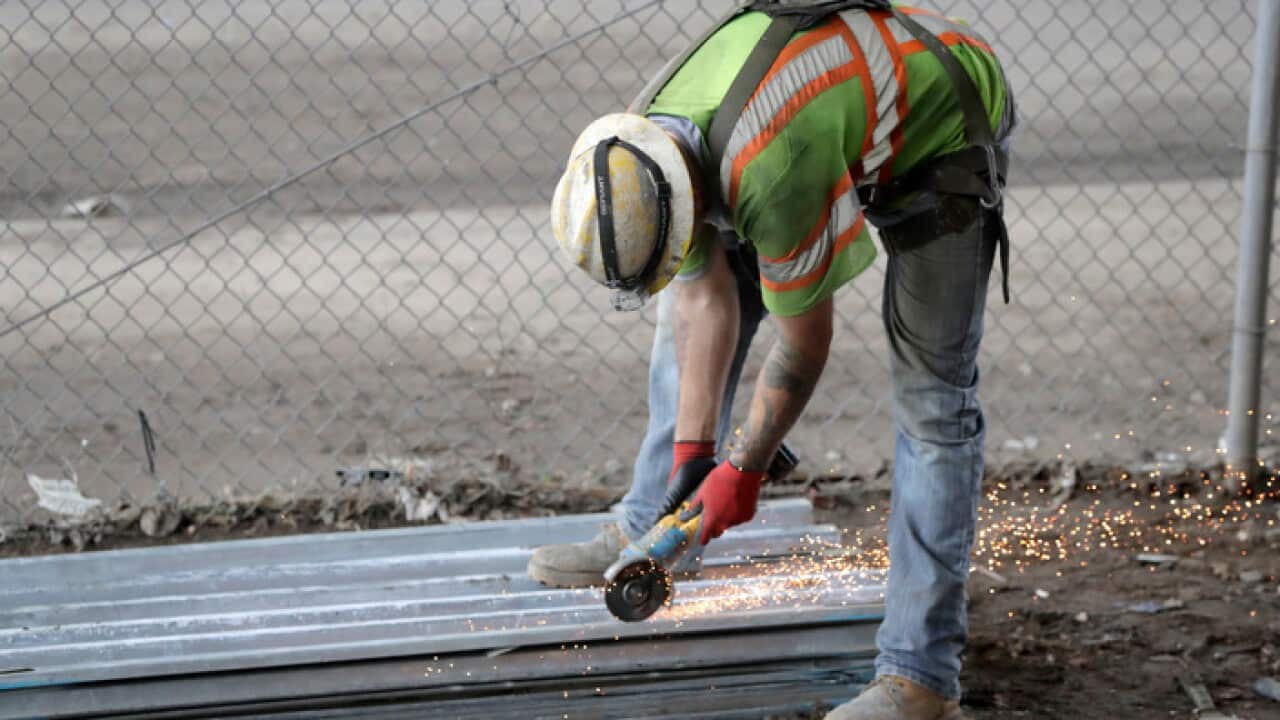 A worker labors on the scaffolding below the Route