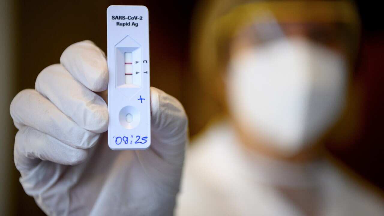 A health worker shows a positive result from a Rapid Antigen Test