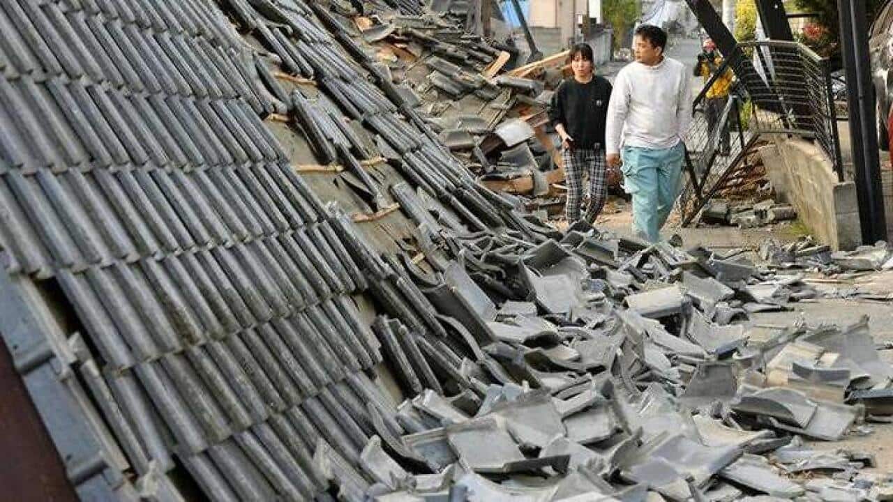 Residents walk along collapsed houses in Mashiki, Kumamoto prefecture, southern Japan, Friday, April 15, 2016, after a magnitude-6.5 earthquake. (AAP)
