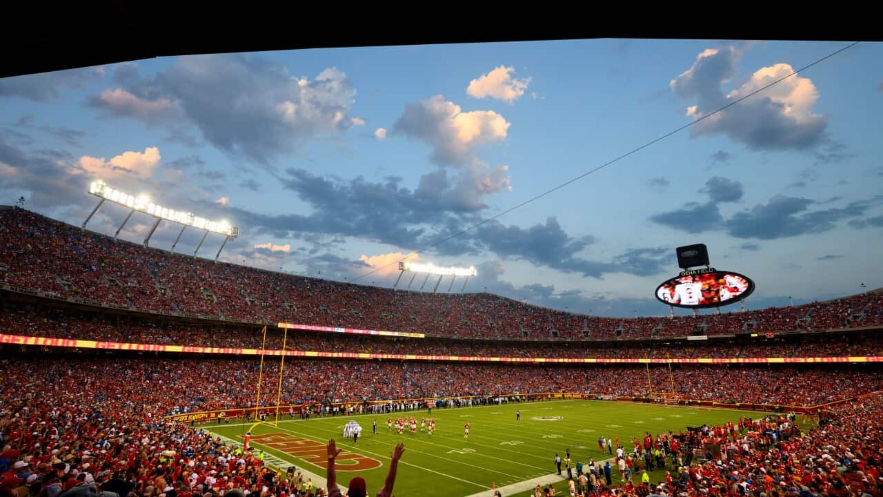 An interior view of a stadium with fans mostly wearing red, with blue sky over the stadium