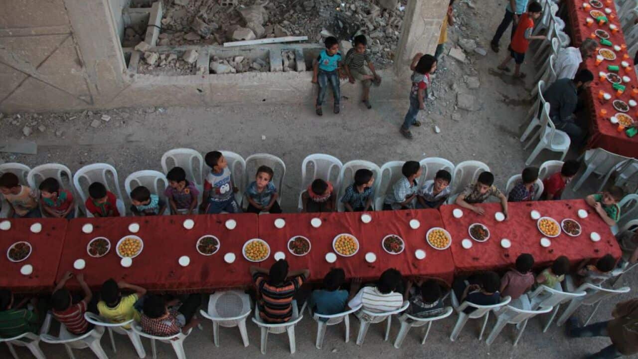 Syrian residents of the rebel-held town of Douma break their Ramadan fast with the "iftar" meal on a heavily damaged street on June 18.