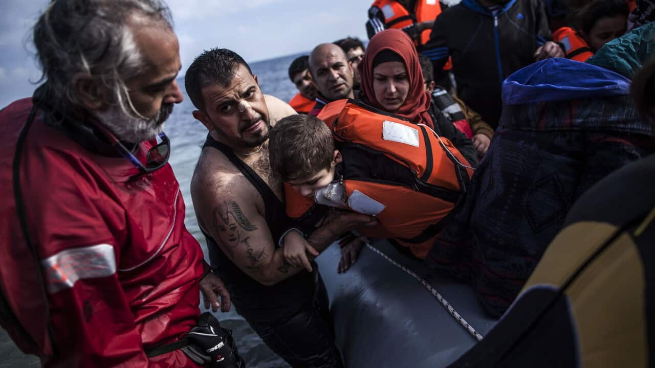 A Syrian man holds his son as they arrive with refugees and migrants on a dinghy from the Turkish coast to Mytilene, Lesbos island, Greece, on Feb. 25.