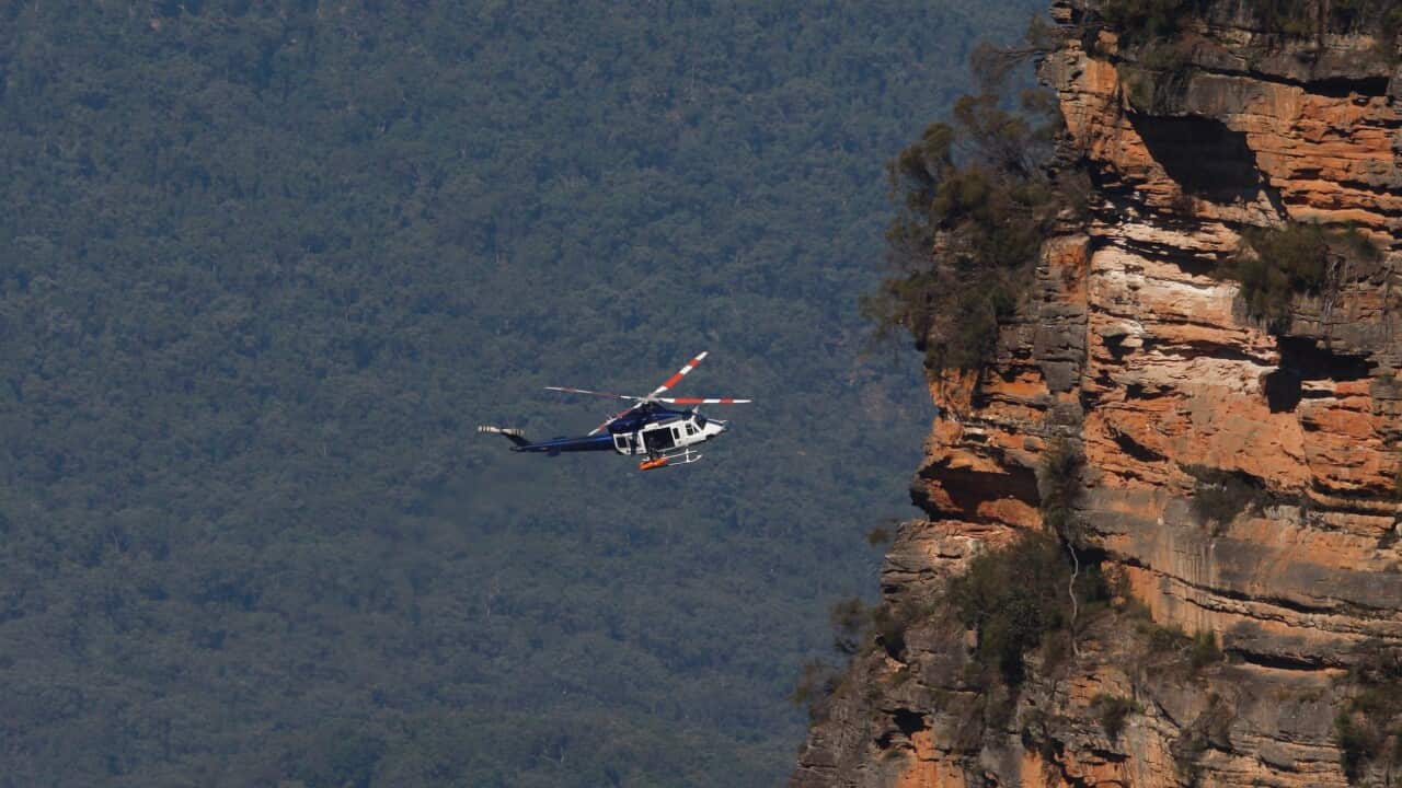 A NSW Police helicopter retrieves the bodies of a father and son from a walking track where a landslide killed 2 and injured two others at Wentworth Falls in the Blue Mountains, NSW, west of Sydney, Tuesday, April 5, 2022. Emergency crews are returning to