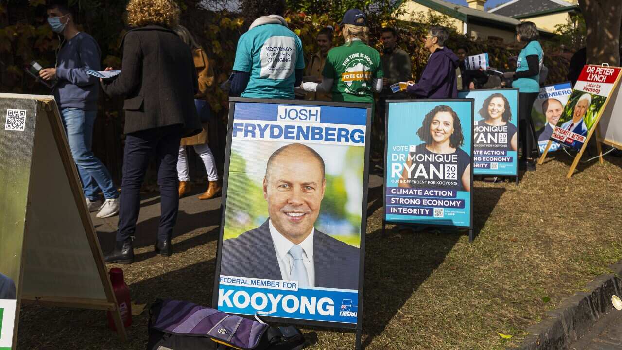 Voters walking along a footpath next to campaign boards.