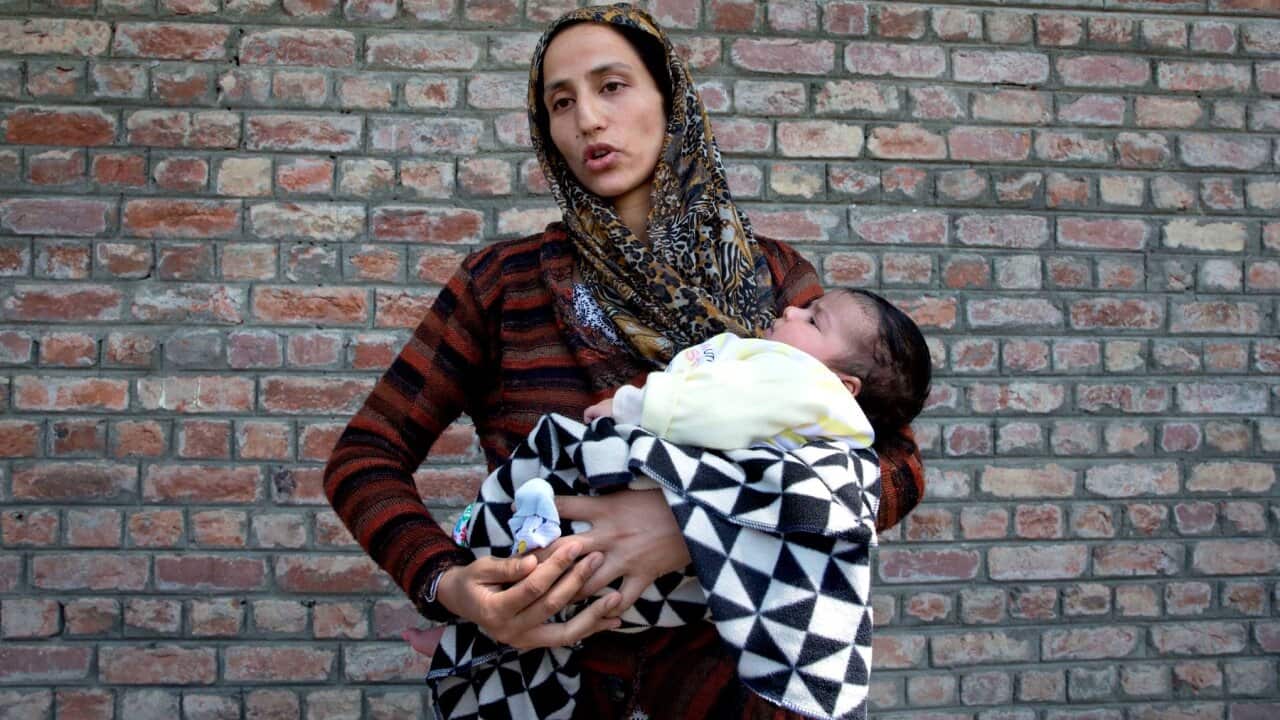 A Kashmiri woman holds daughter outside a police station to hear about her husband detained during night raids in Srinagar, Aug 20, 2019.(AP Photo/ Dar Yasin)