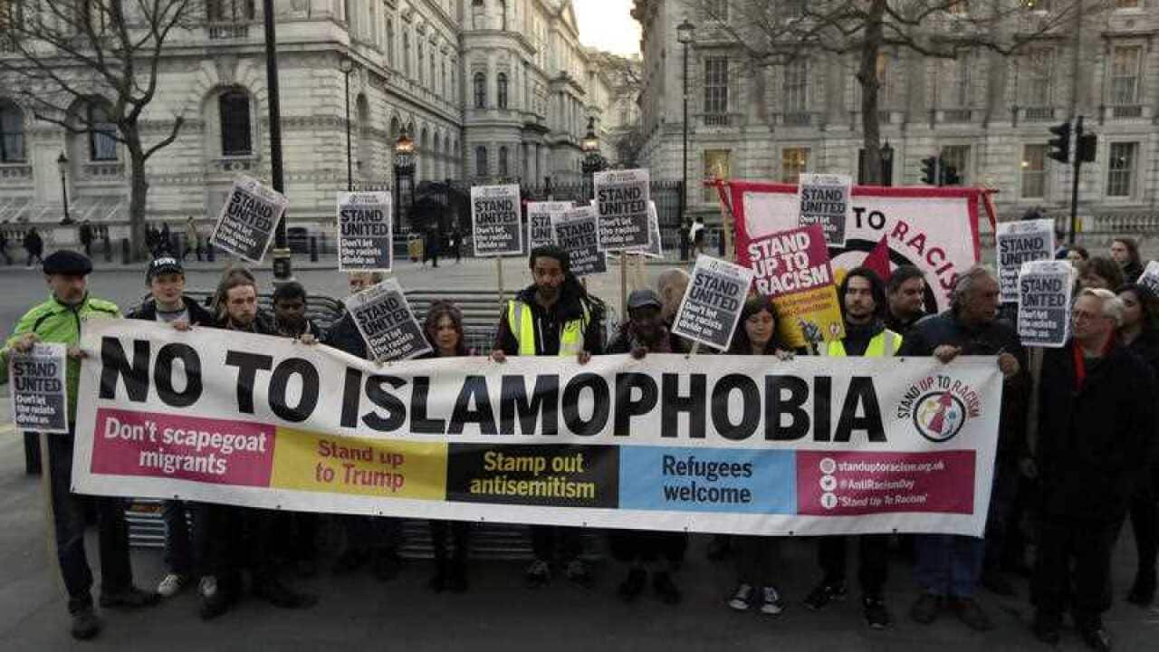 People hold up a banner during a 'Unity Vigil' against racism and Islamophobia in reaction to Wednesday's attack, backdropped by the gates of Downing Street in London, Friday March 24, 2017.