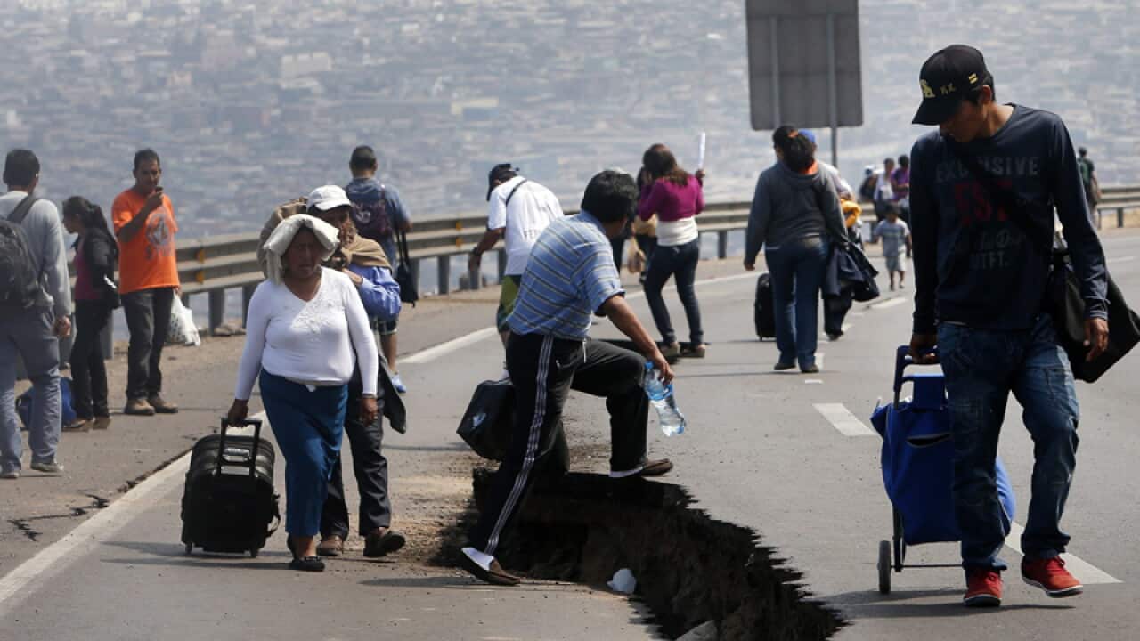 A group of people walk over a crack in a highway
