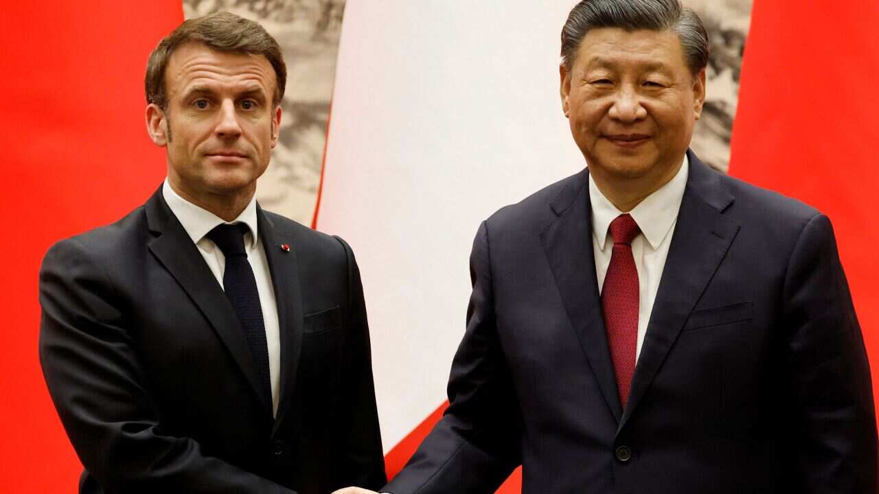 Two men in dark suits shake hands