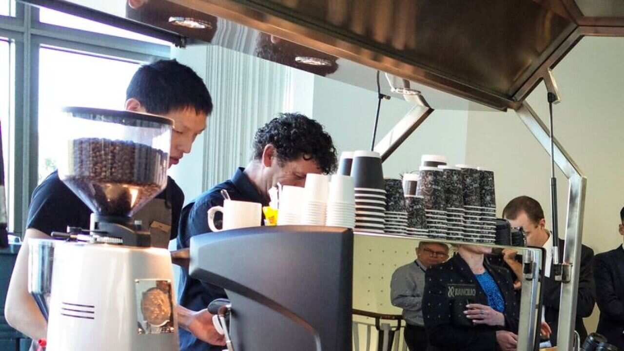 People line up to make orders at a coffee cart