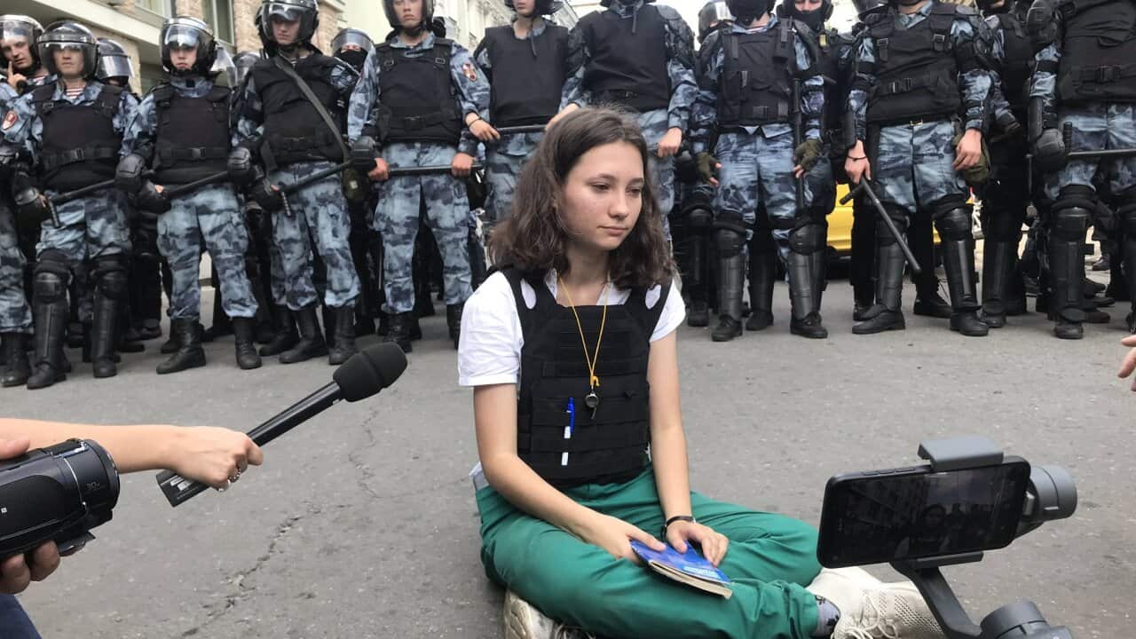 Olga sits cross-legged in front of riot police with the Russian constitution on her lap,