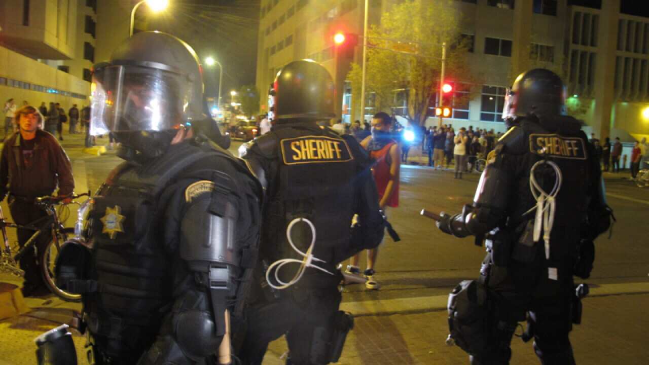 Riot police stand guard in front of protesters in Albuquerque