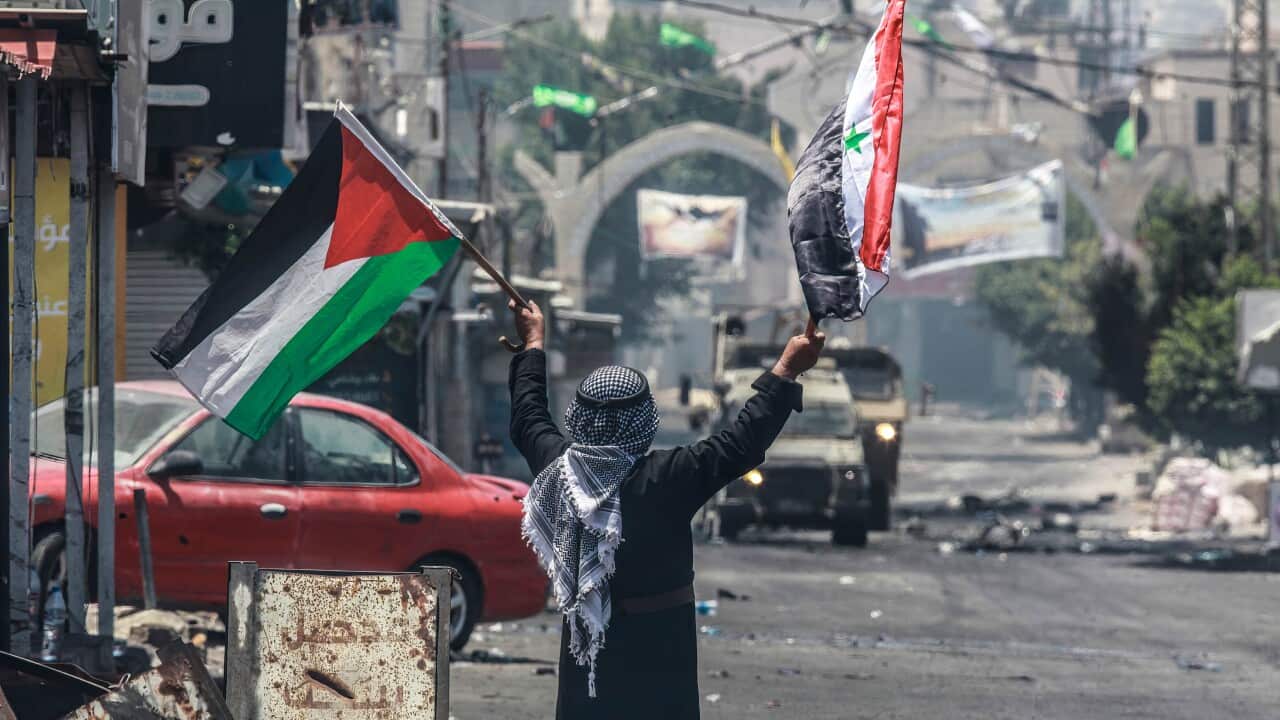 A Palestinian confronts Israeli military vehicles with the Palestinian and Syrian flags to prevent them from crossing into the center of Jenin refugee camp.