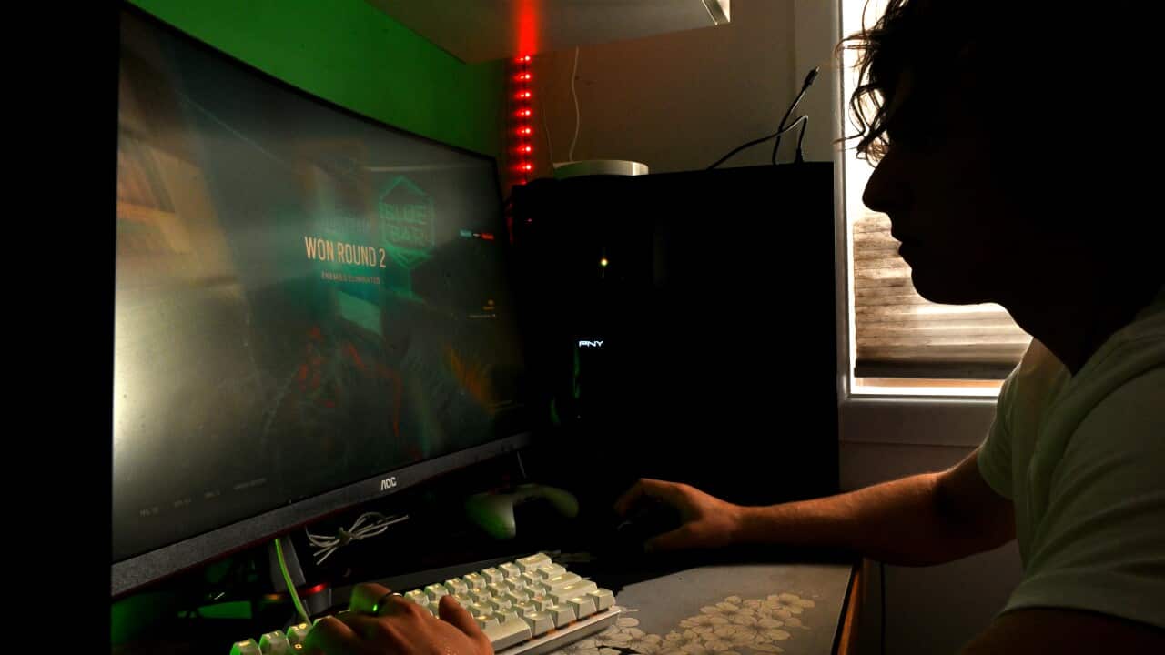 A person playing a video game at their computer in a dark room.