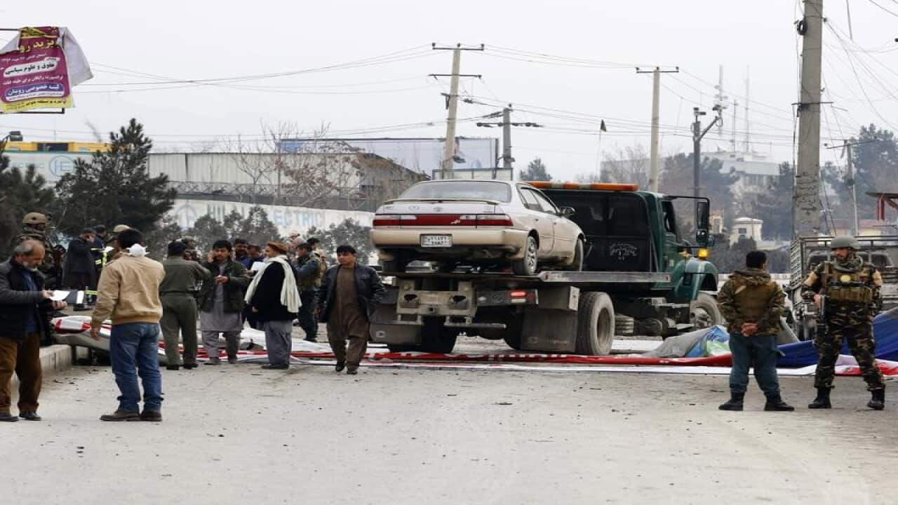 Security officials inspect the scene of the car bomb attack in Kabul